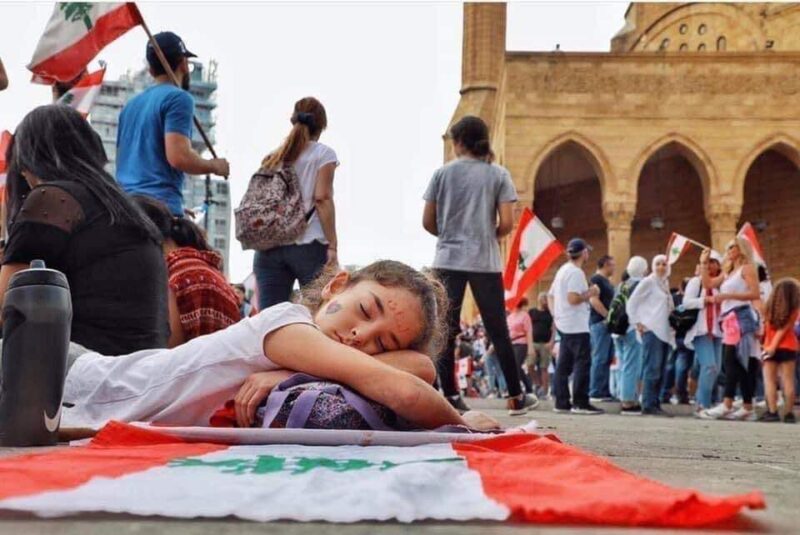 A young girl rests on a Lebanese flag at a protest in Beirut in 2019.