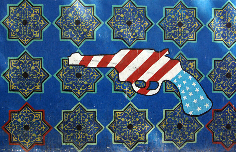 A pistol in the colors of the American flag is stamped on a wall of Iranian geometric patterns.