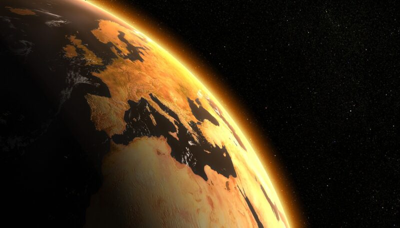 An orange-tinted globe is backlit against a black background. Europe and the tip of Africa are visible.