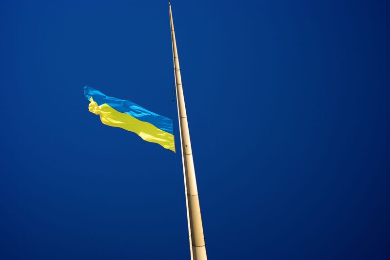 A photo of a Ukrainian flag, shot from below on a deep blue sky.