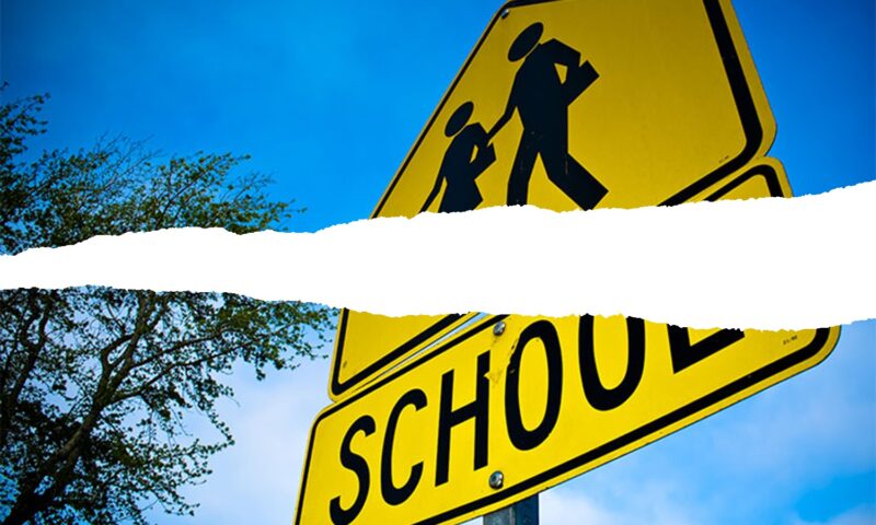 A school crossing sign, split across the middle with a jagged white line as if torn in two.