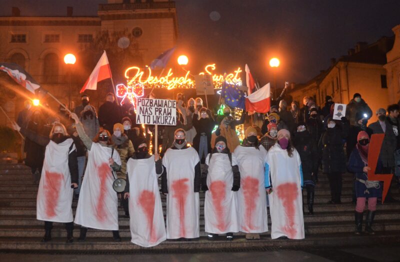Protests against abortion restriction in Poland, December 2020. People at the front of the protest hold long white rectangles stained with red, evoking bloody menstrual pads.