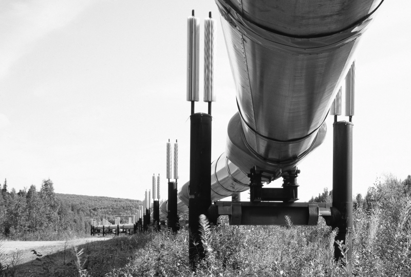 Black and white photograph shot from under a gas pipeline.