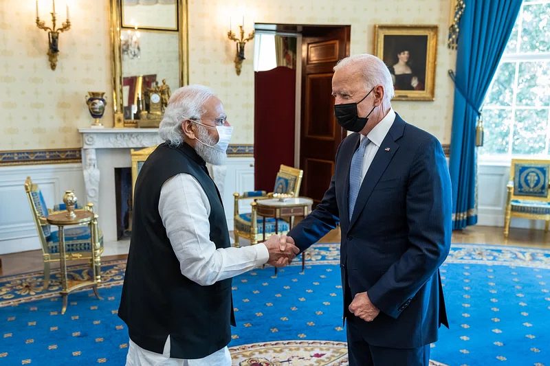 President Joe Biden receives Prime Minister Narendra Modi with a handshake at the White House. Both wear masks.