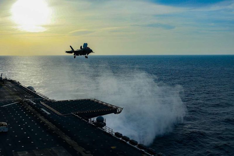 A naval carrier and fighter plane, backed by the sun and photographed on the South China Sea in 20200. There are no obvious national markings on either vehicle, but the plane is an F-35B Lightning.