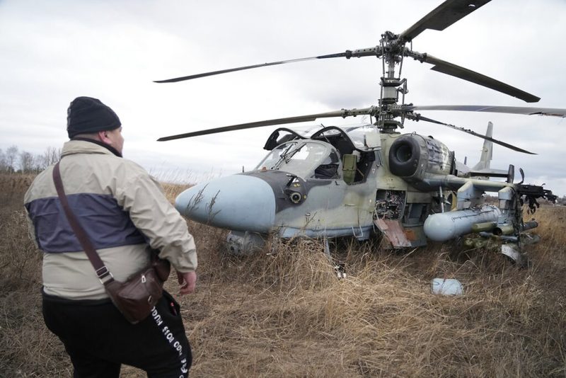 A man stands in front of a Russian Ka-52 helicopter gunship, having taken a forced landing outside Kyiv. Photo taken Feb. 24, 2022.