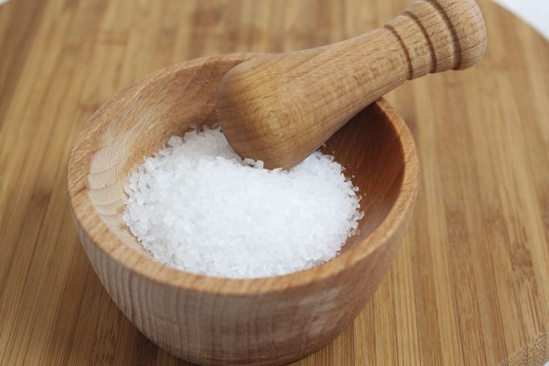A wooden mortar and pestle filled with sea salt.