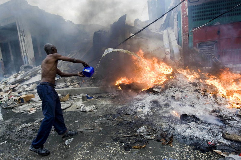 A man attempts to put out a fire on a rubble-filled street in Port-au-Prince after the 2010 quake.